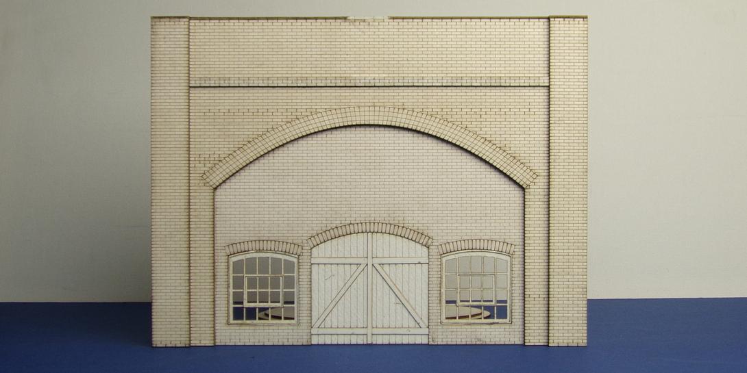 A 70-02 O gauge brick arch with warehouse fittings O gauge brick arch unit with warehouse gate and two windows. This bundle includes the face of the arch and the back parapet panel with interlocking left and right brickwork.